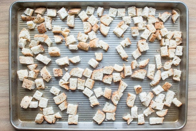 Top down shot of cut up cubes of gluten free bread on a metal sheet pan.