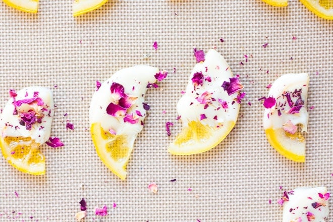 white chocolate candied lemons with edible rose petals on a mat