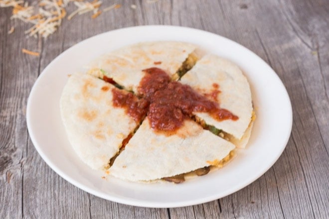 easy gluten free breakfast quesadilla cute into fourths on a white plate with salsa on top