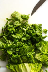 cutting up leaves of green lettuce