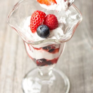 Spoon scooping a bite of Simple Summer Berry Paleo Parfait out of a parfait glass