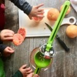 kids squeezing grapefruits with a juicer into a cup