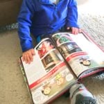 little boy flipping through a cookbook on the floor