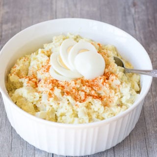 large bowl of instant pot gluten free potato salad in a white bowl with a spoon on the right side