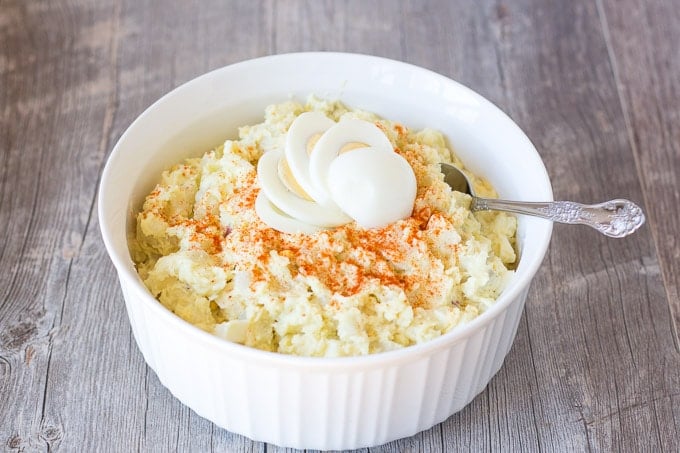 large bowl of instant pot gluten free potato salad in a white bowl with a spoon on the right side
