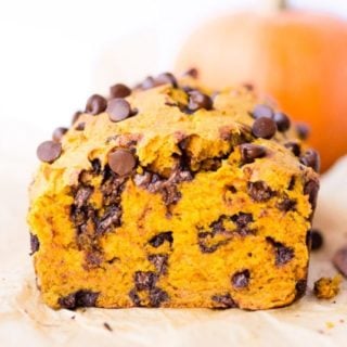 straight on shot of a loaf of chocolate chip pumpkin bread with a pumpkin in the background
