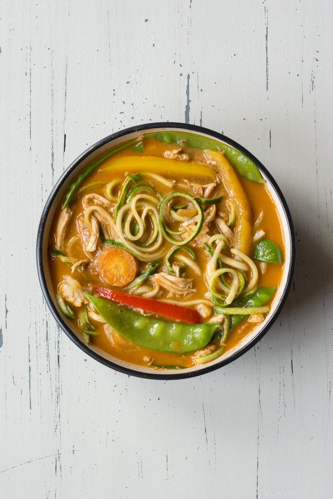top down view of chicken curry zoodle bowl on an off-white background