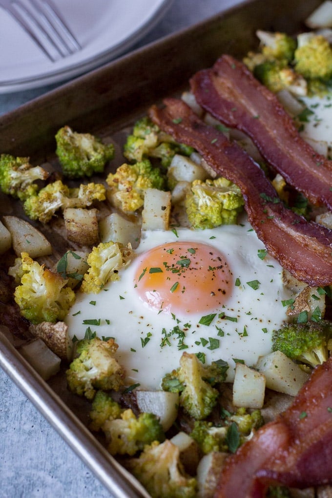 zoomed in shot of a cooked egg on a sheet pan with potatoes, romanesco and bacon for this Easy Sheet Pan Breakfast dish