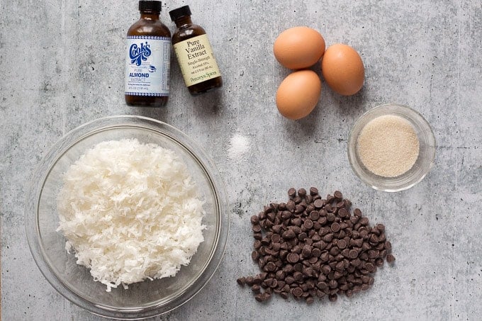 top down shot of ingredients for chewy coconut macaroons - extracts, eggs, sugar, coconut, chocolate chips, and salt