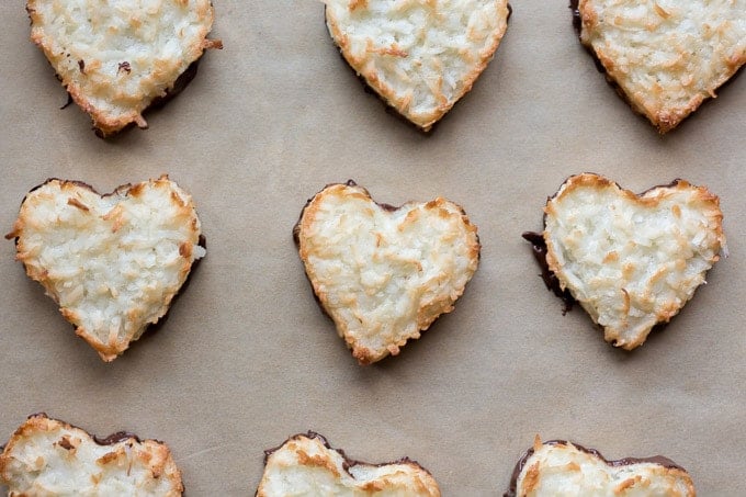 top down view of chocolate dipped chewy coconut macaroon hearts on parchment paper