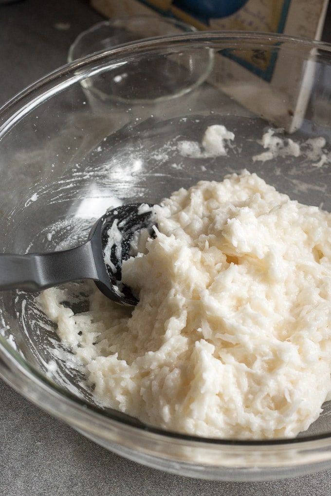 zoomed in view of coconut macaroon mixture in large pyrex bowl with a black spatula on the side