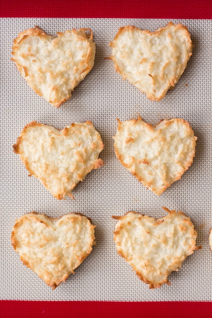 top down view of cooked chewy coconut macaroon hearts on a silicone baking mat