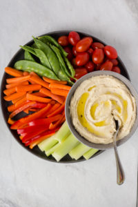 top down view of roasted garlic cashew dip on a plate surrounded by veggies