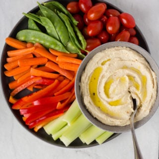 top down view of roasted garlic cashew dip on a plate surrounded by veggies
