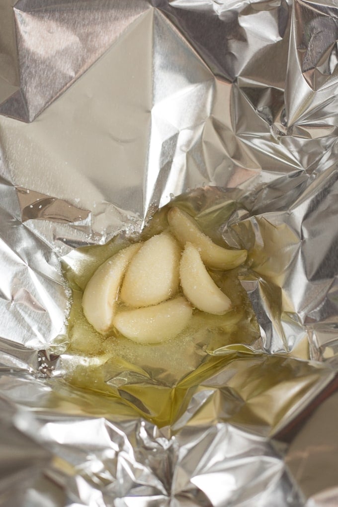Five cloves of garlic with oil and salt in aluminum foil.