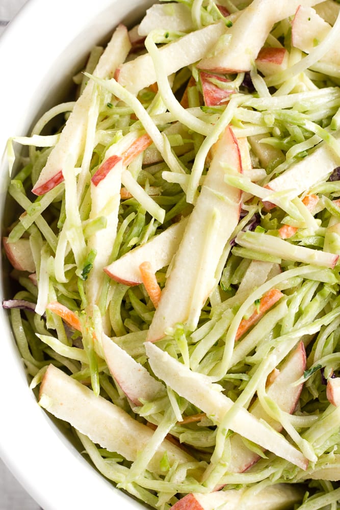 Zoomed in top down shot of apple broccoli slaw in a large white bowl.