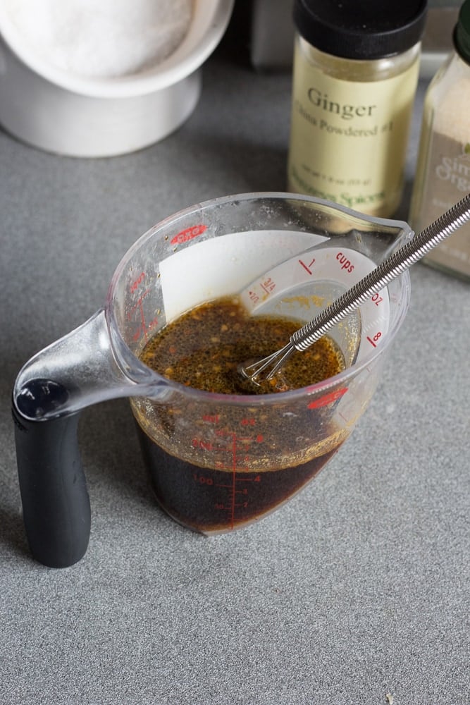 Stir fry sauce in a measuring cup with a whisk on a gray countertop.