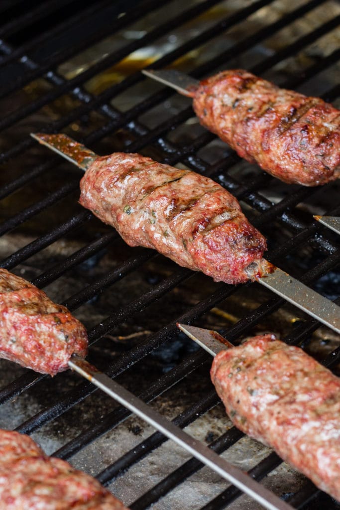 Close up of ground lamb skewers on a grill.