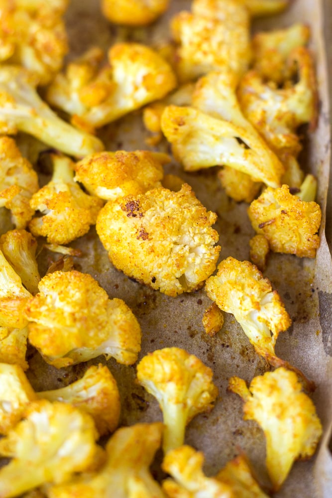Close up of roasted cauliflower on a sheet pan with brown parchment paper underneath.