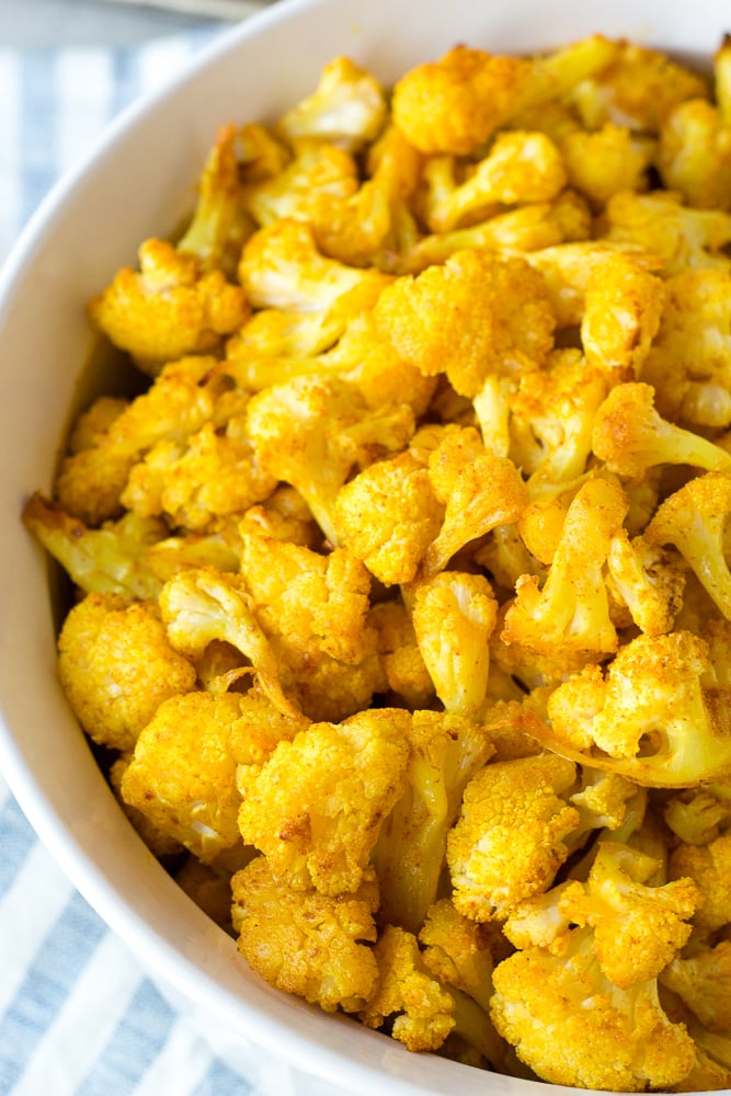 Close up of turmeric roasted cauliflower in a large white bowl.