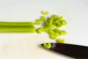 chopping celery on a cutting board for corn chowder