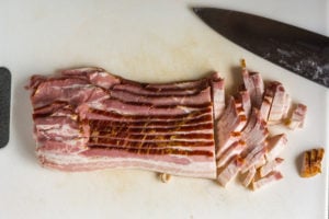 bacon being cut on a cutting board