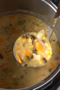 lifting bacon corn chowder out of the instant pot with a ladle