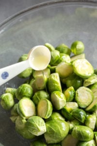 pouring oil over cut brussels sprouts