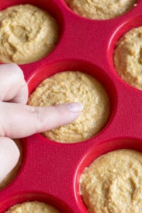 finger smoothing unbaked cornbread muffin