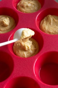 scooping out cornbread mixture into muffin pan