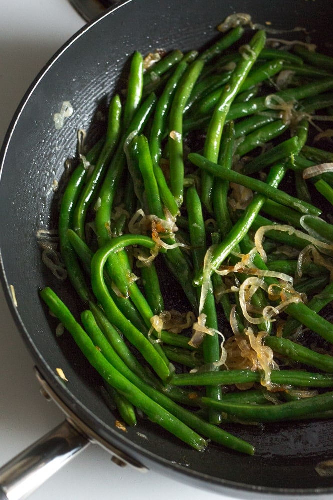 cooked green beans and shallots in a pan
