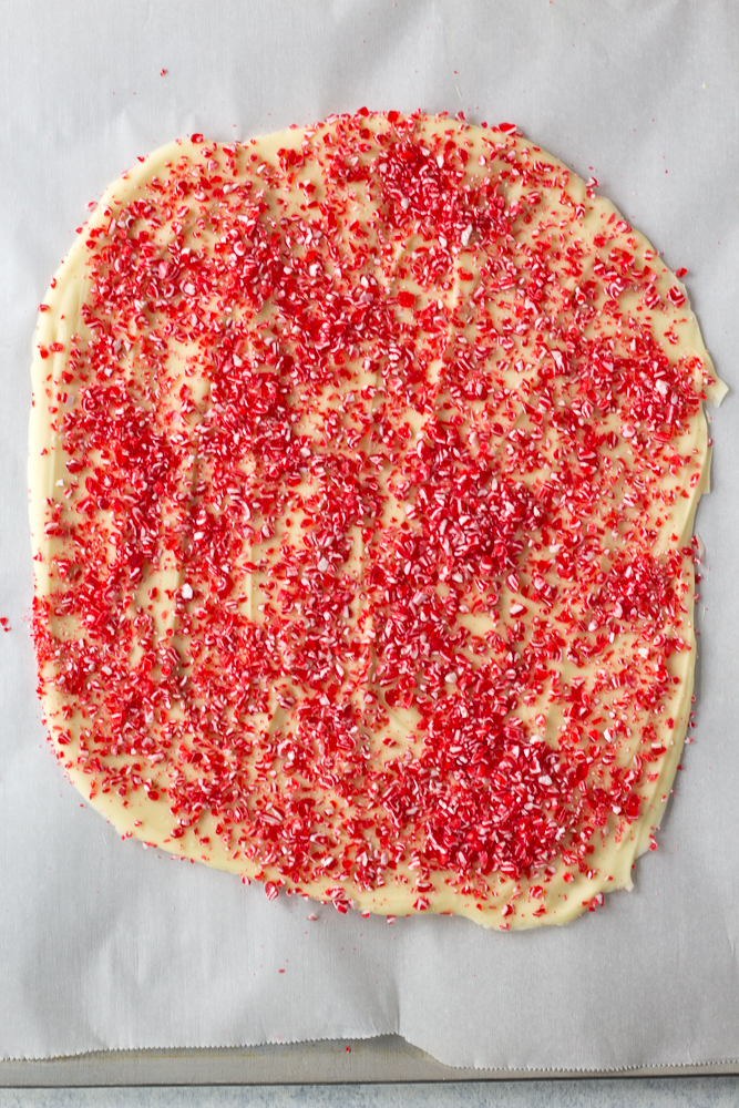 A top down shot of a parchment-lined sheet pan of this white chocolate peppermint bark recipe.