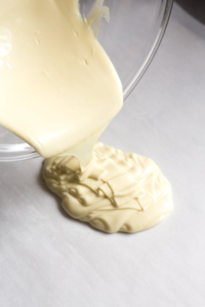 White chocolate being poured on parchment paper.