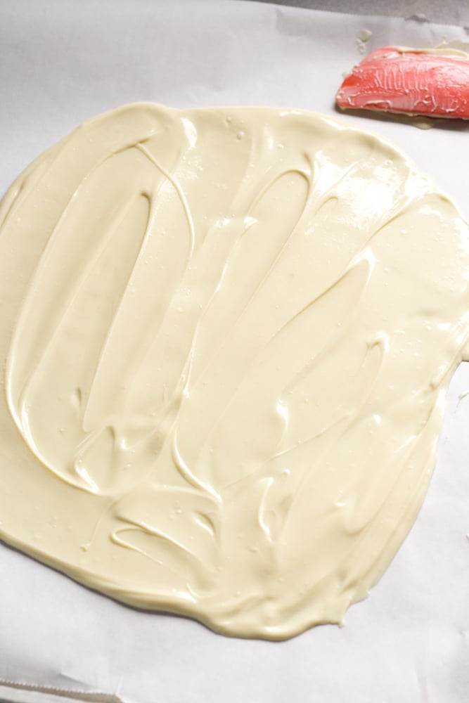 Spread out white chocolate on a parchment-lined sheet pan.