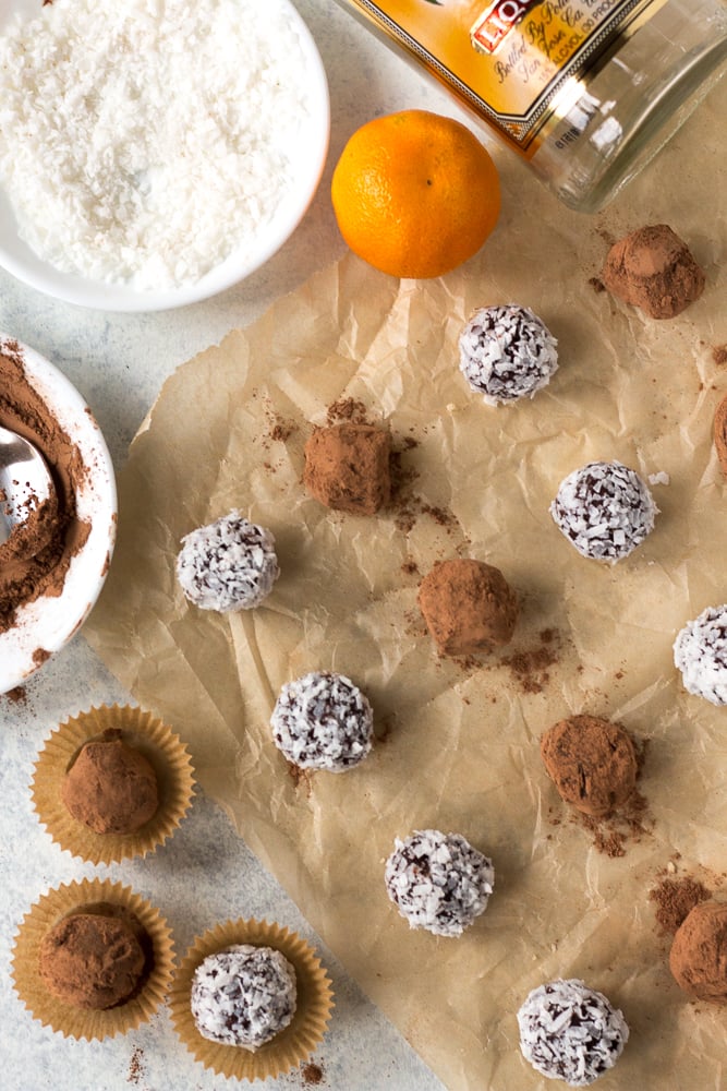 boozy chocolate truffles on a piece of brown parchment paper with accompaniments surrounding them.