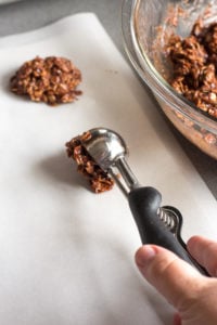 placing a scoop of no bake chocolate oatmeal peanut butter cookies onto parchment paper