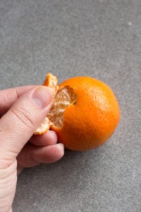 a hand peeling an orange
