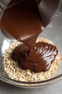 pouring chocolate over oats in a bowl