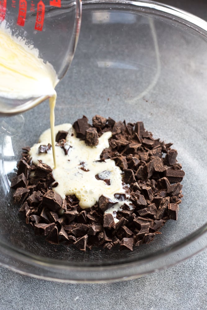 pouring cream onto chocolate pieces in bowl.