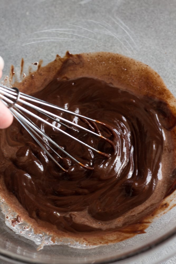 whisking melted chocolated in a clear bowl.