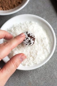 rolling a boozy chocolate truffle in coconut flakes