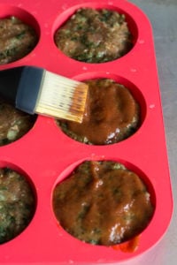 brushing ketchup on paleo meatloaf muffins