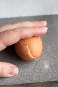 rolling a hard boiled egg to crack it.