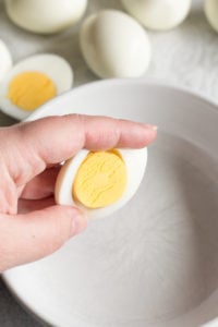 popping the yolk out of a cut hard boiled egg