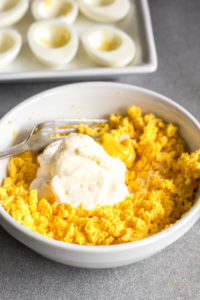 mashed egg yolks in a bowl with ingredients for deviled eggs