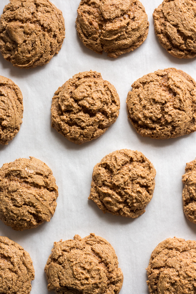 Top down shot of cooked almond butter cookies on a parchment-lined cookie sheet.