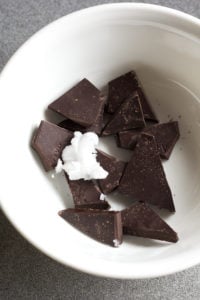 pieces of chocolate with coconut oil in a small white bowl