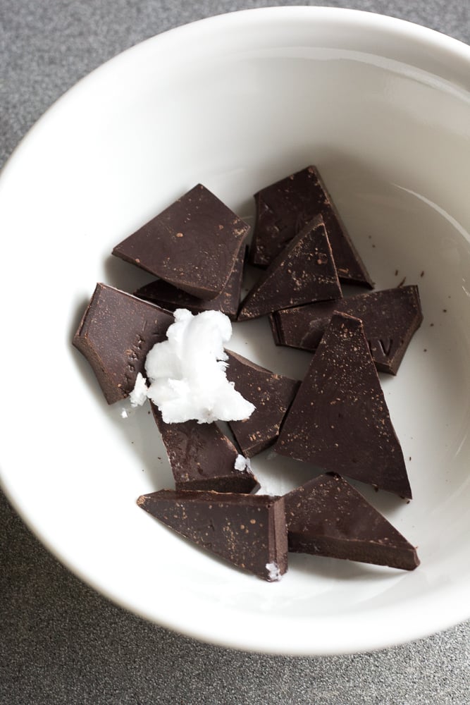 Pieces of chocolate with coconut oil in a small white bowl.