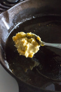 placing a scoop of potato mixture in a skillet