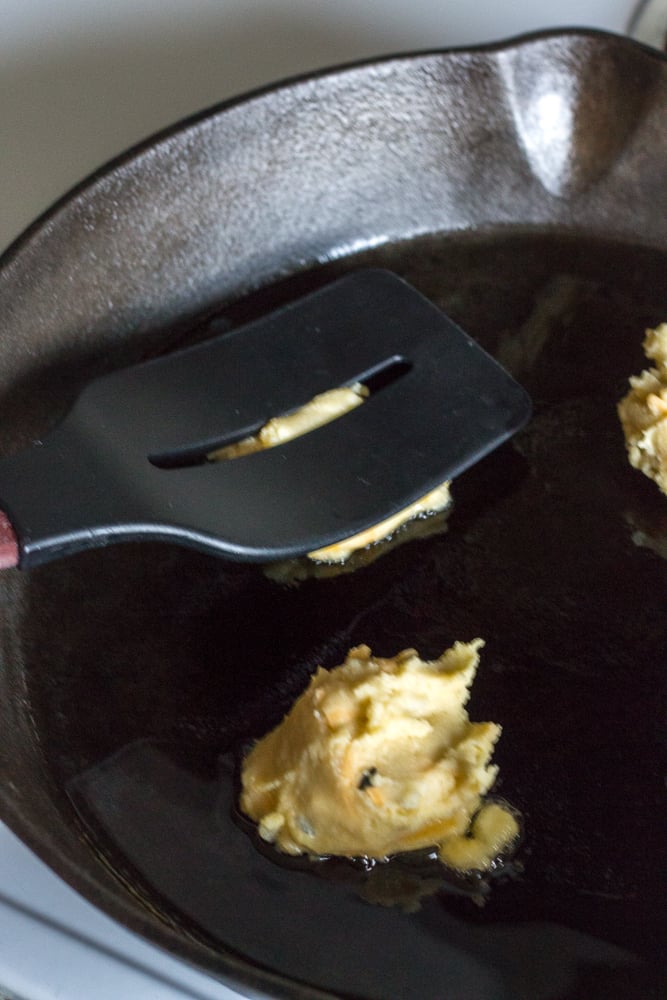 Flattening potato mixture in the skillet with a spatula.